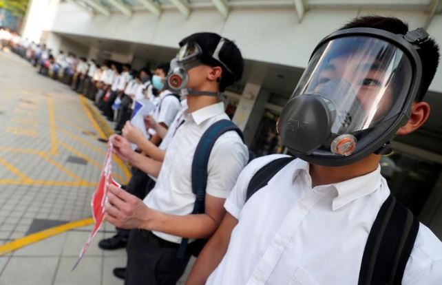 طلاب من المدارس الثانوية يرتدون أقنعة يشكلون سلسلة بشرية تأييدا للمحتجين المناهضين للحكومة في هونج كونج يوم الاثنين. تصوير: عمرو عبد الله دلش - رويترز